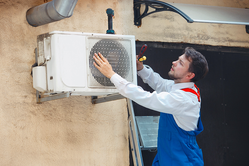 HVAC technician working on a capacitor part for condensing unit. Male worker or repairman in uniform repairing and adjusting conditioning system, diagnosting and looking for technical issues.
